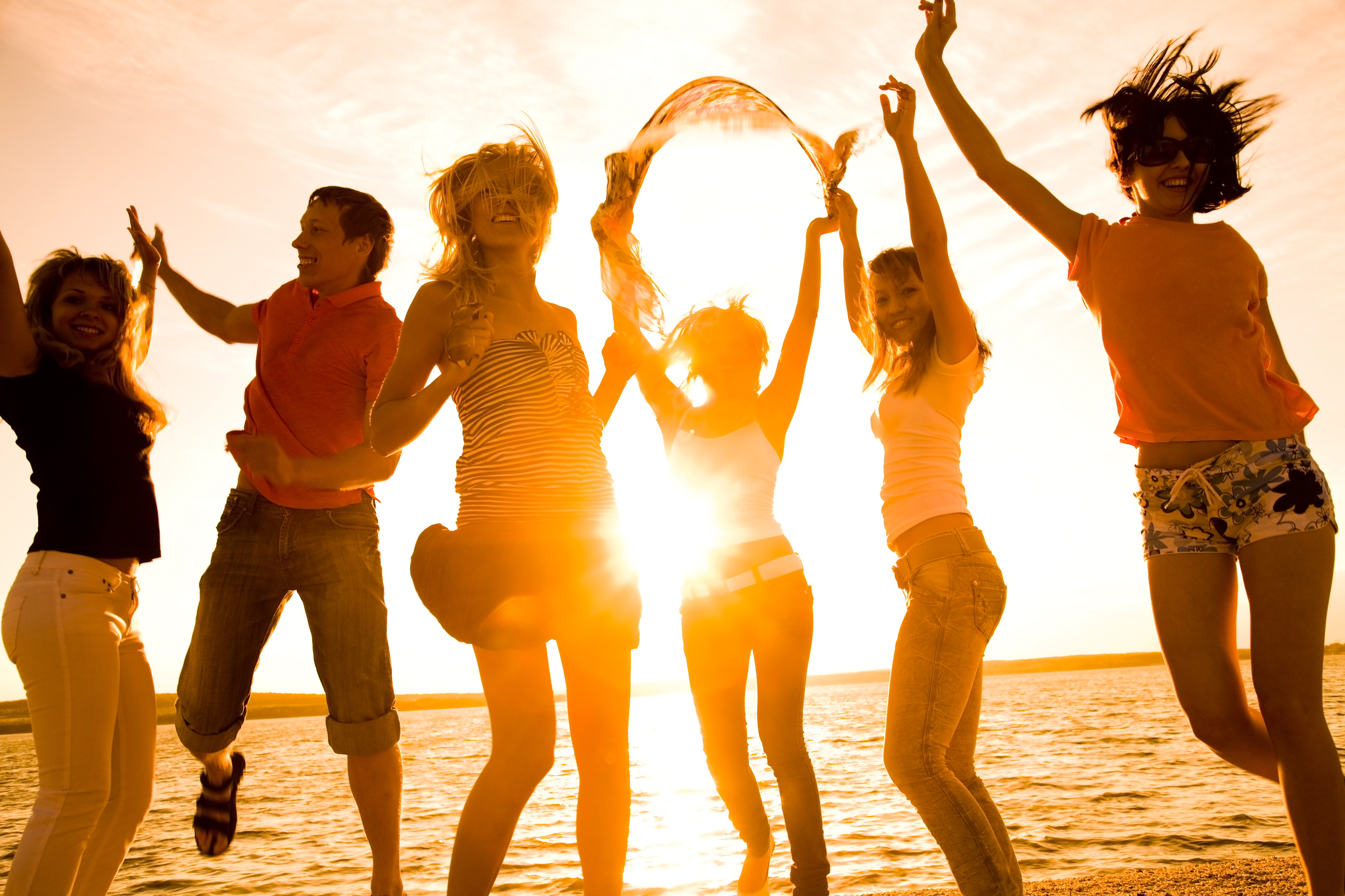 a group of young people dancing on the beach